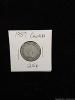 Obverse side of 1957 Canadian silver quarter showing Queen Elizabeth II profile and inscriptions with the coin secured in a cardboard holder.