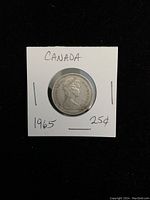 Obverse side of the 1965 Canadian silver quarter showing Queen Elizabeth II profile on coin in cardboard holder.
