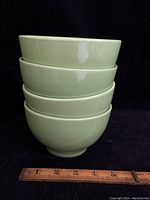 Stacked set of four light green porcelain bowls with ruler showing width and height.