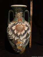 Full view of the antique Japanese Moriage vase with double handles and floral raised design shown next to ruler for scale.