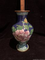 Front view of a Chinese cloisonné vase showing large pink flower and brass rim.