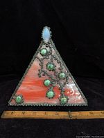 Full view of the triangular leaded glass piece with green decorative stones and orange-white swirled glass. A ruler is included for scale showing approximately 6.5 inches in width.
