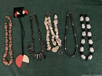 Six necklaces arranged in a row, two sets with matching accessories visible on the sides