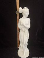 Full view of the white alabaster statue of Aphrodite with ruler to show height, approximately 13 inches tall, solid figure with detailed hair and drapery.