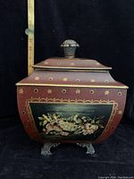 Front view of the rectangular toleware box showing painted bird and fruit motif with ruler next to it to show size about 8.5 x 11 inches