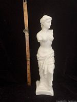 Full view of white bisque Venus de Milo statue showing approximate height by ruler.