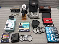 Overview of the lot showing various camera accessories, filters, cases, film rolls, and cameras.