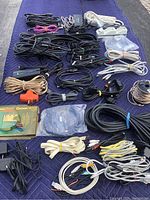 Overview photo of assorted wires and cables spread on dark fabric, showing multiple bundles of speaker wire, power cords, audio cables, and adapters.