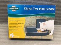 Box showing the PetSafe Digital Two Meal Feeder with a cat eating from it.