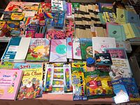 Wide overview of the lot featuring children's books, a variety of crafts and art supplies including colored pencils, erasers, markers, and activity pads.