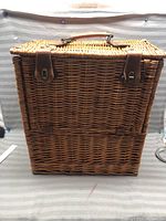 Wicker picnic basket closed front view showing leather straps and handle