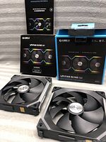 Two black Lian Li UNI Fan SL140 V2 RGB fans displayed outside of original packaging, showing front blades and magnetic connection points.