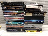 Photo of stacked DVD movies showing titles on the spines including Avalon, Hamlet, Friday Night Lights, Don Cherry, The Lost Medallion, and Black Adder.