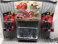 Photo showing multiple Disney Infinity figures including two Darth Maul Star Wars 3.0 edition figures, Cars red race car, Toy Story Buzz Lightyear, and a Star Wars battle pack with two figures.