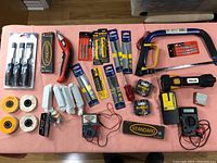 Tools spread out showing full lot including drill bits, chisels, hacksaw, rotary tool, measuring tape, multimeter, polishing wheels