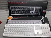 Two ultra slim Macally USB wired keyboards displayed with packaging box in background