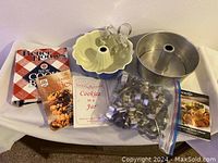 View of all items including three cookbooks, two cake pans, and metal cookie cutters