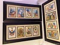 Two black wood frames each holding four vintage patriotic postcards featuring American flags, eagles, and medals, arranged in a row.