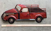 Full view of red metal truck wall logo on concrete floor with measuring stick below showing length about 41 inches.
