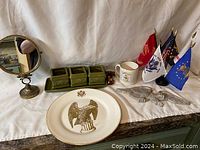 Overview of all lot items including mirror, green planter set, eagle plate, mug, metal eagle figurine, and flags.