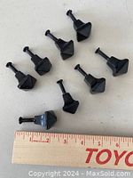 Set of eight black cast metal knobs with screws for scale showing size next to a ruler