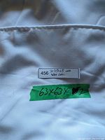 Close-up photo of white table cloth with label showing size 63x63 inches and item count 2