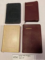 Top view of four antique mini religious books arranged on a white surface, showing color and cover details