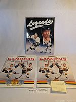 Photo showing two Vancouver Canucks 1993/94 coin albums Series 1 and 2 and one 1991 sports memorabilia guide with Wayne Gretzky on the cover