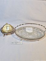 Full view of vintage divided pressed glass caviar dish with ornate silver handle holder alongside a separate silver footed caviar dish with dome lid.