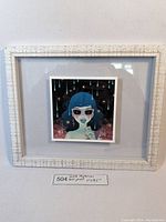 Framed Jenna McPherson mini print with white textured frame, depicting a blue-haired woman with sunglasses and a cosmic background.