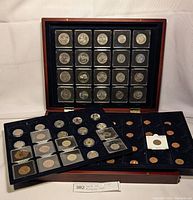 Closed mahogany case with three tiers, top tray displayed upright showing coins in capsules, two removable trays below with additional coins in capsules and flips.
