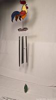 Full length view of the stained glass wind chime showing rooster and metal chime tubes and green glass gem
