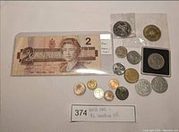 Canadian $2 bill and assortment of world coins and vintage tokens.