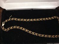 Full view of the gold plated necklace laid flat inside a black jewelry box.