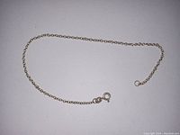 Single fine silver-colored anchor link chain bracelet laid flat on white background showing full length and clasp detail.