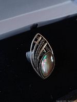 Close-up of the adjustable silver plated ring showing the abalone marquise shaped centerpiece and intricate metal design.