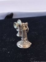 Front side view of the antique candlestick telephone charm showing detailed mouthpiece and receiver with slight tarnish on sterling silver surface.