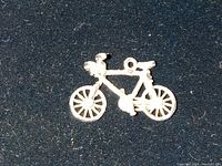 Close-up photo of the silver bicycle charm on a black background showing the entire charm intact.