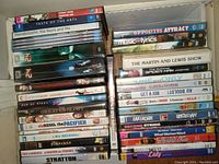 Photo of mixed DVD movies in cases stacked showing variety of genres and titles.