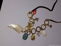 Full view of mother of pearl tiger claw necklace with various gemstone and metal charms on a leather cord.