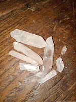 Photo showing nine clear quartz crystal points of various sizes and shapes on wooden surface.