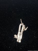 Close-up of sterling silver ski charm showing skis and cross poles against black background