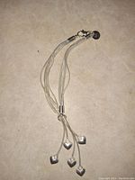 Full view of the sterling silver bracelet with its five heart charms spread out on a tiled surface.