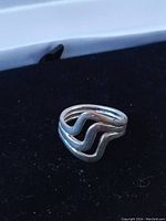 Front-angle view of the sterling silver ring showing the triple band wave design and its silver-toned polished finish.