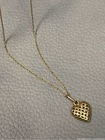 Close-up photo of the 10k gold heart pendant showing woven basket design.