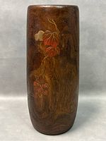 Front view of tall cylindrical dark wood vase with painted bird and leaf decoration.