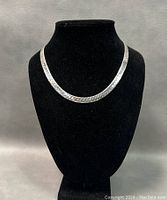 Front view of the flat chain necklace displayed on a black jewelry bust showing length and design.