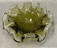 Top view of the art glass ashtray showing the swirling amber-green glass pattern and eight clear textured handles around the rim.