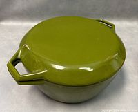 Top view of green cast iron pot with fitted lid showing olive green glossy finish and dual handles on lid.