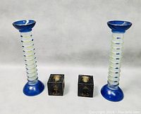 Photo showing the two blue and white spiral glass candlesticks alongside two small black metal cube candle holders